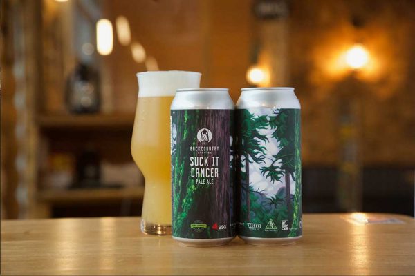 Backcountry Brewing | About Us - Suck It Cancer can and glass on a table